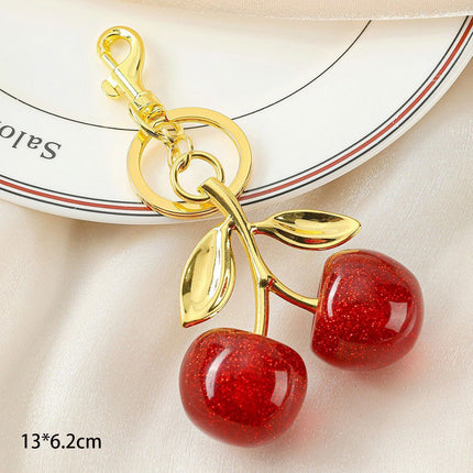 Elegant Red Cherry Bag Charm with double golden leaves, holding lovely little luck to accompany your trips out